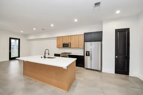 a large white kitchen with a refrigerator a sink dishwasher a stove and a refrigerator with wooden floor