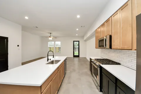 a kitchen with granite countertop a sink stove and cabinets