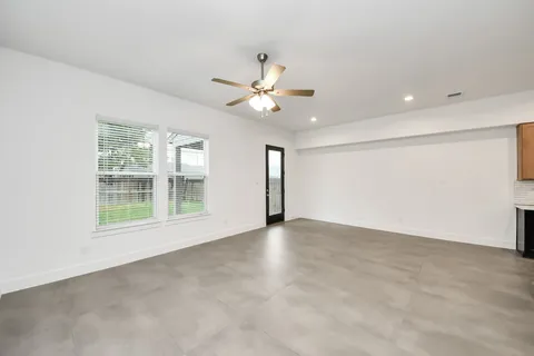 an empty room with chandelier fan and windows