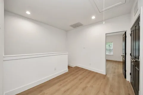 a view of an empty room with chandelier fan and wooden floor