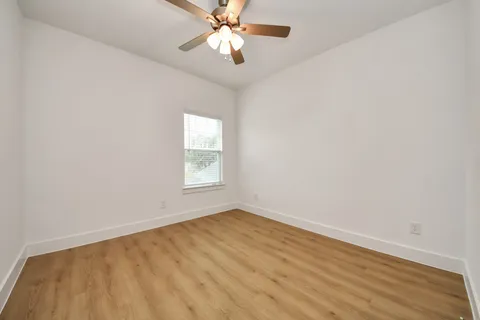 an empty room with a window and a fan