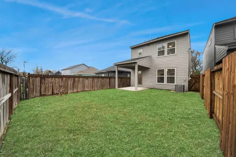 a view of a house with backyard and wooden fence