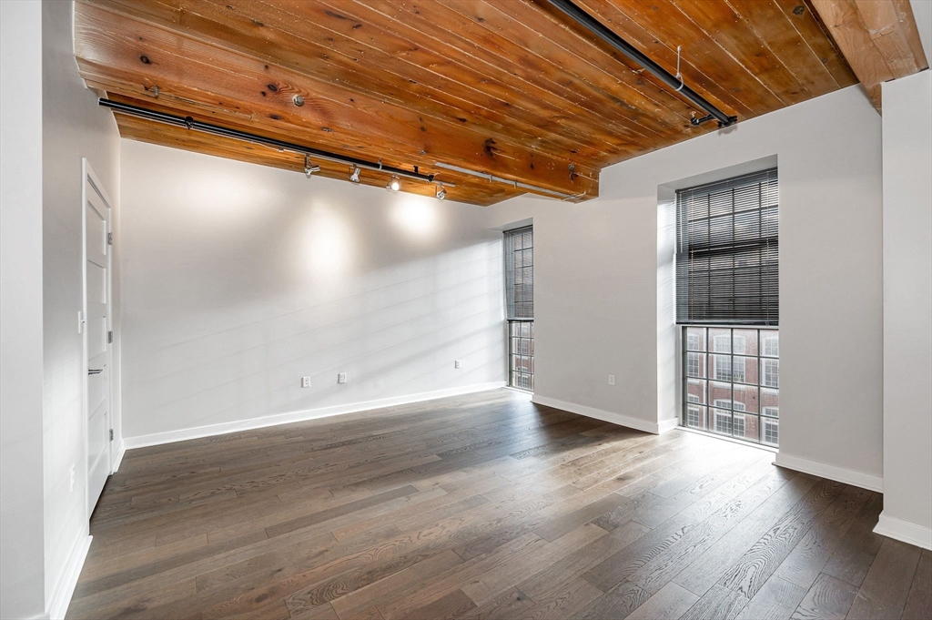 130 John Street, Unit 355 Lowell, MA 01852 - Photo 12 of 34 an empty room with wooden floor and windows