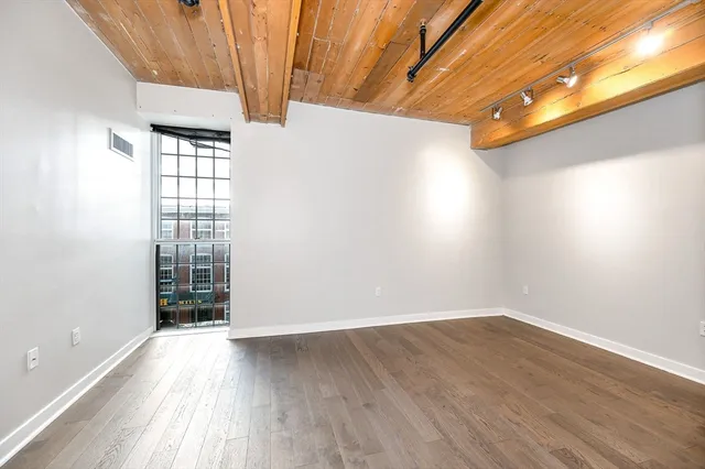 an empty room with wooden floor and windows