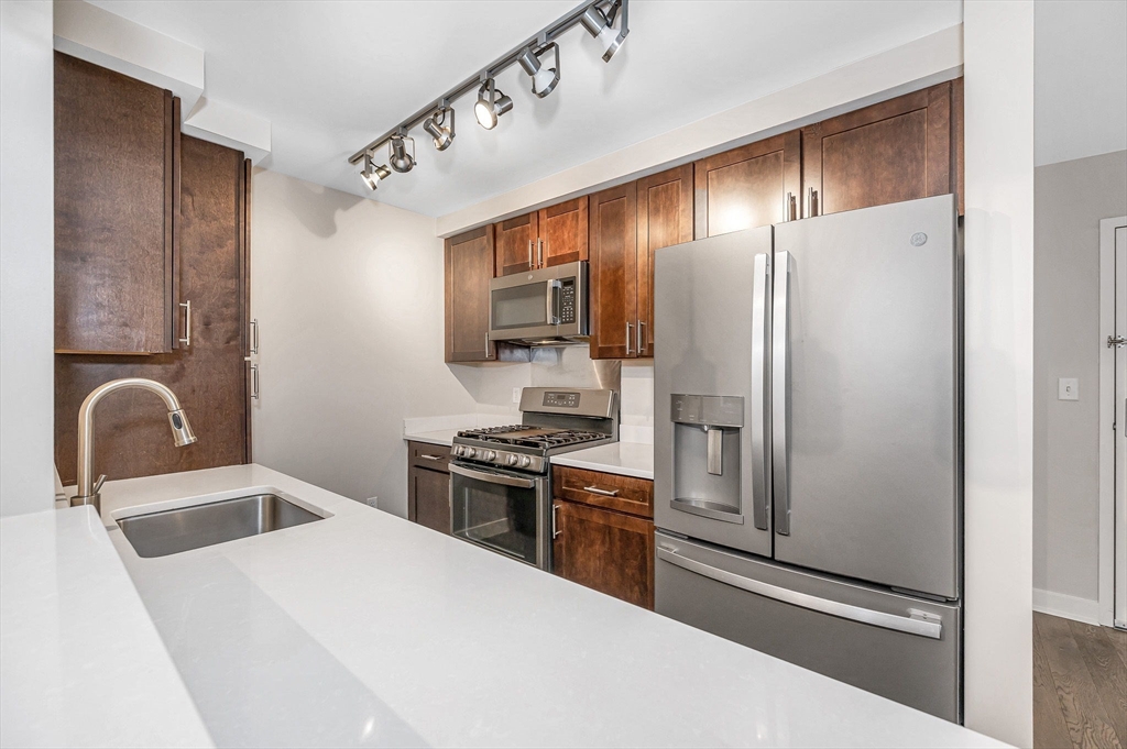 130 John Street, Unit 355 Lowell, MA 01852 - Photo 2 of 34 a kitchen with stainless steel appliances granite countertop a refrigerator a stove and a sink with wooden floors