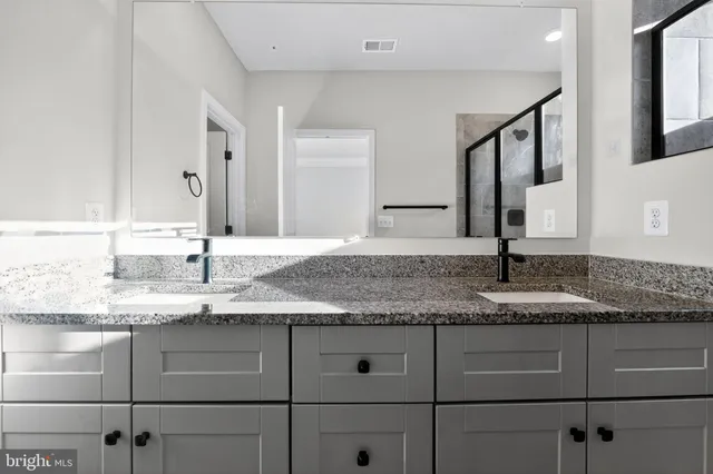 a bathroom with a granite countertop double vanity sink and mirror