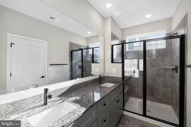 a bathroom with a granite countertop sink mirror and shower