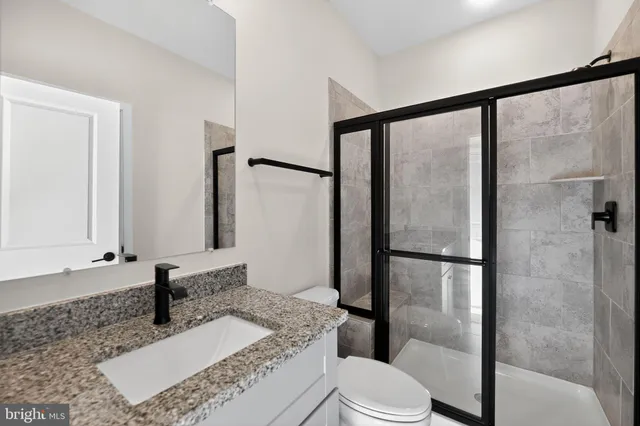 a bathroom with a granite countertop sink toilet and shower