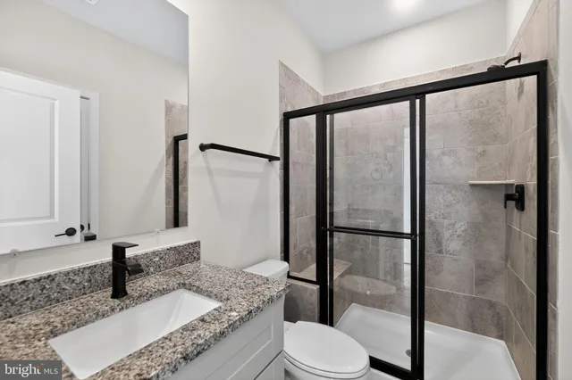 a bathroom with a granite countertop sink mirror vanity and toilet