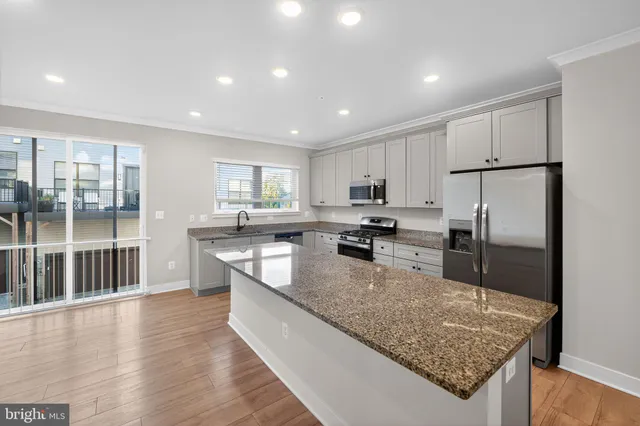 a large kitchen with kitchen island a large counter top stainless steel appliances and cabinets