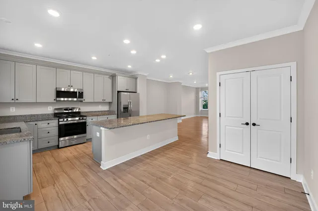 a large kitchen with stainless steel appliances granite countertop a large counter top a stove and a wooden floors