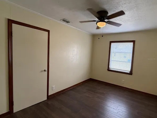 a view of an empty room with wooden floor and a window
