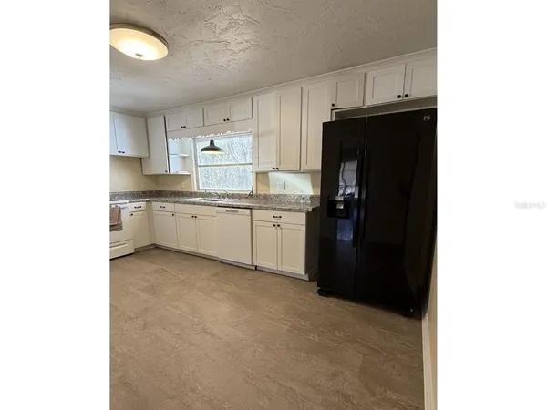 a kitchen with a sink dishwasher a refrigerator and cabinets