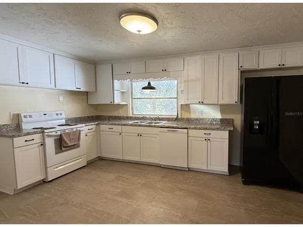 a kitchen with granite countertop white cabinets and white appliances