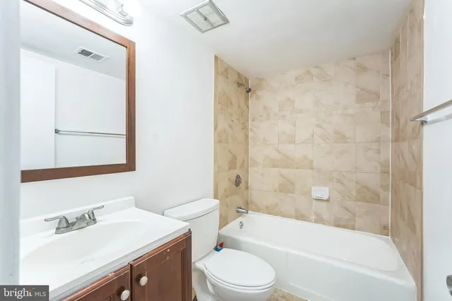 a bathroom with a bathtub shower sink vanity mirror and toilet