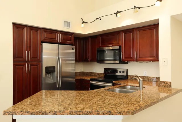 a kitchen with stainless steel appliances granite countertop a refrigerator a stove top oven a sink and dishwasher