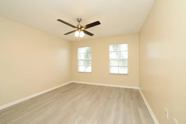a view of empty room with wooden floor and fan