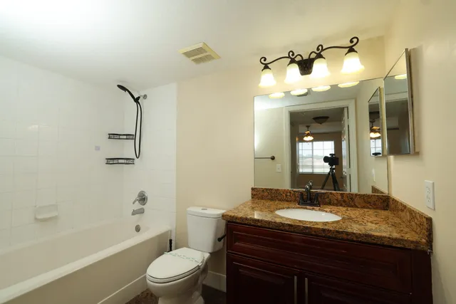 a bathroom with a granite countertop sink toilet a mirror a bathtub and shower