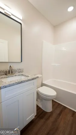 a bathroom with a granite countertop toilet sink and mirror