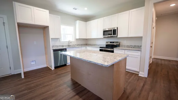 a kitchen with granite countertop white cabinets and wooden floor