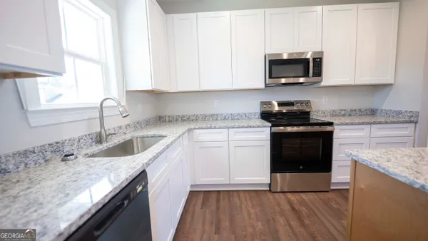 a kitchen with stainless steel appliances granite countertop a sink stove microwave and refrigerator