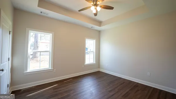 a view of an empty room with a window and wooden floor