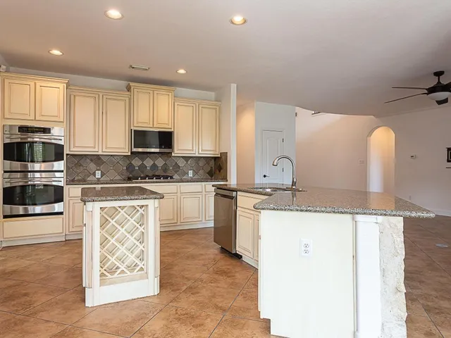 a kitchen with granite countertop a sink a counter top space appliances and cabinets