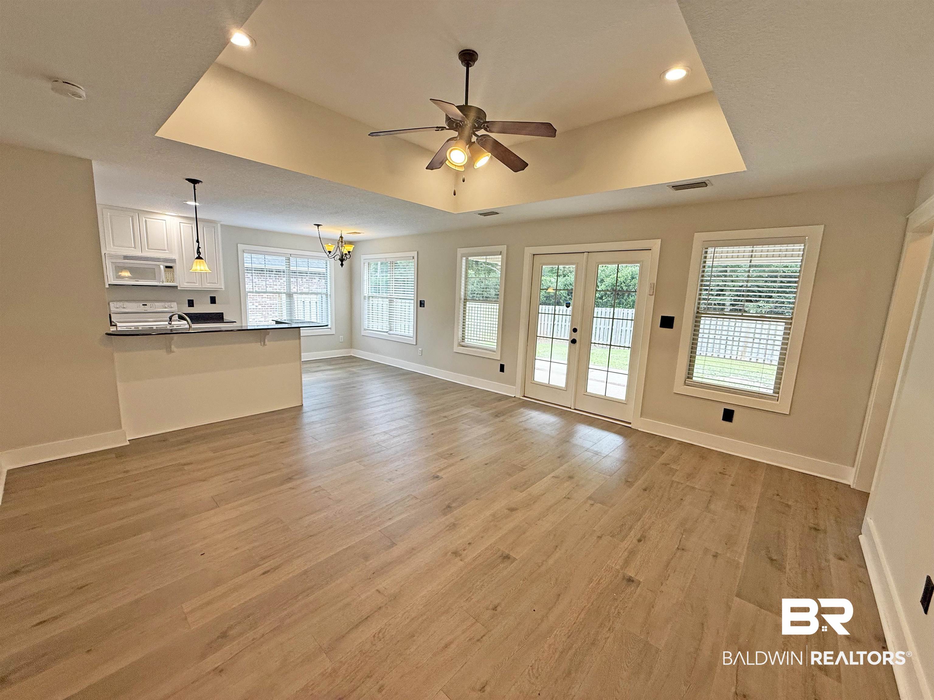 22023 Garland Loop Silverhill, AL 36576 - Photo 7 of 33 Unfurnished living room featuring a raised ceiling, light wood finished floors, a ceiling fan, recessed lighting, and a chandelier