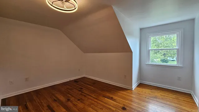 a view of an empty room with wooden floor and window