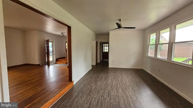 a view of a hallway with wooden floor and a living room