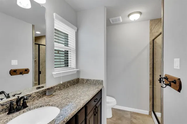 a bathroom with a granite countertop sink toilet and mirror