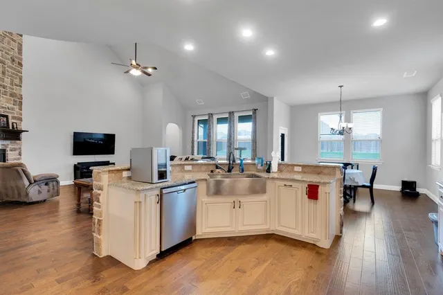 a large white kitchen with a large island in the center and wooden floor