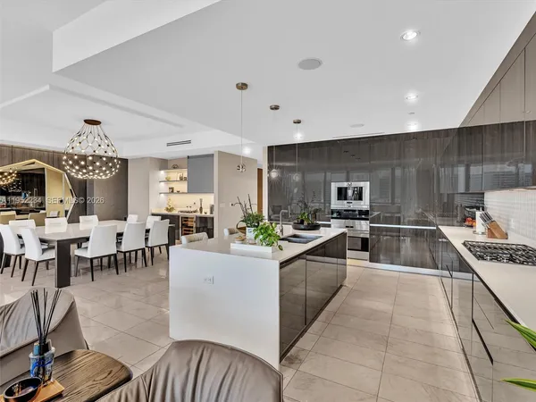 a kitchen with stainless steel appliances a stove a sink a oven a dining table and chairs