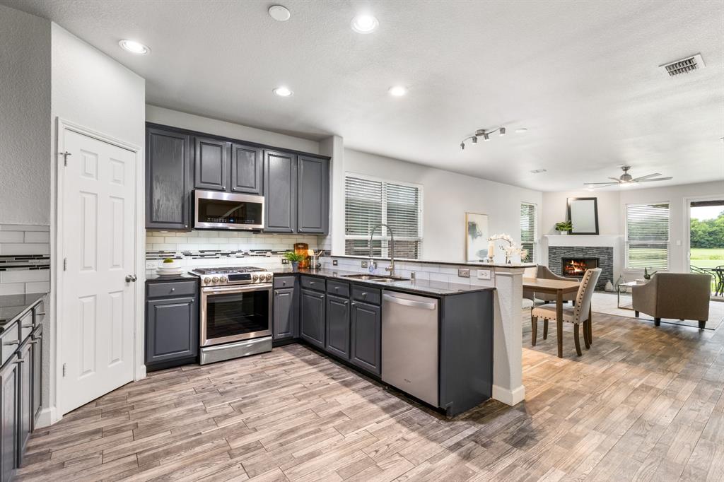 528 Highland Ridge Drive Wylie, TX 75098 - Photo 1 of 1 outdoor kitchen with stainless steel appliances kitchen island granite countertop a stove top oven a sink dishwasher a dining table and chairs with wooden floor