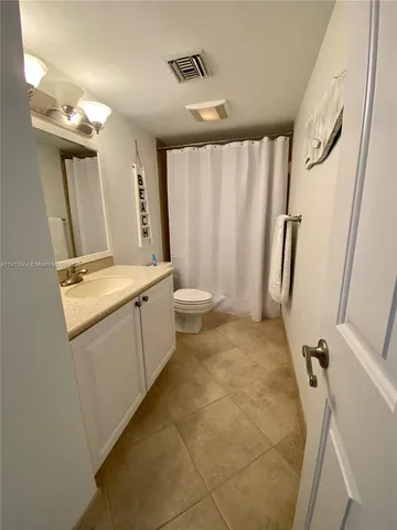 a bathroom with a granite countertop sink a toilet and a mirror