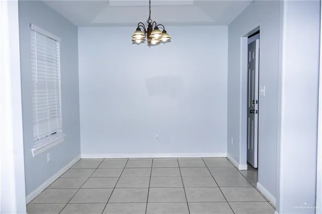 a view of an empty room with a chandelier fan