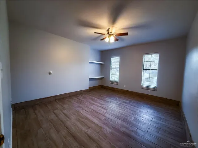 a view of an empty room with a window and wooden floor