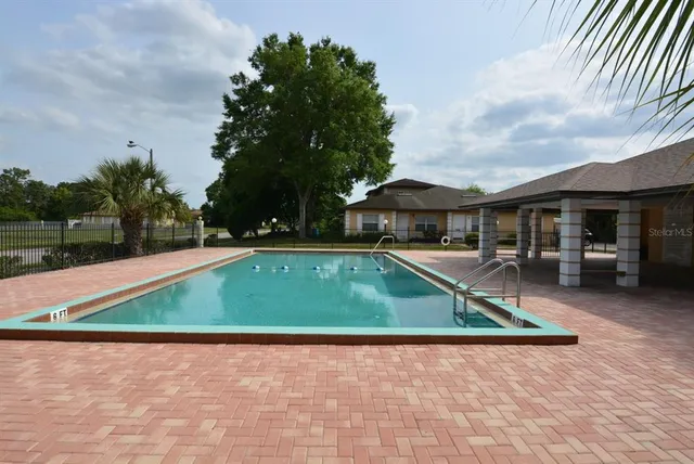 a view of swimming pool with lawn chairs and plants