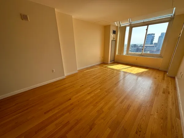 a view of an empty room with wooden floor and a window