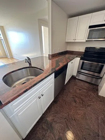 a view of a refrigerator in kitchen and an empty room