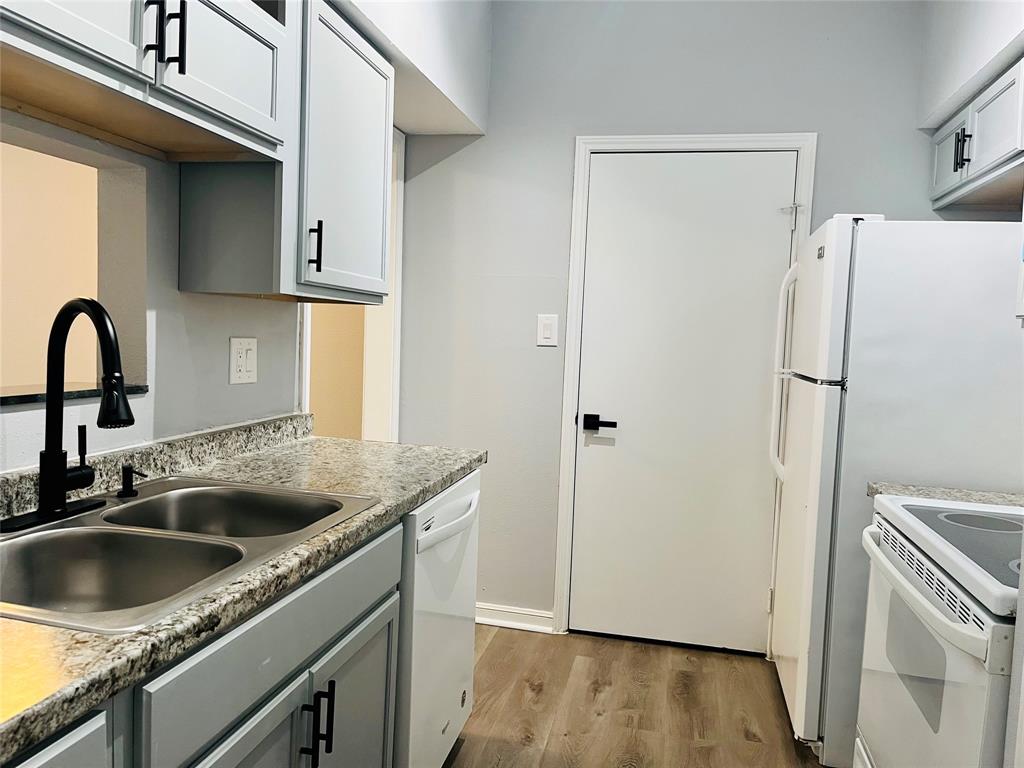 a kitchen with stainless steel appliances granite countertop a sink a refrigerator and a stove with wooden floor
