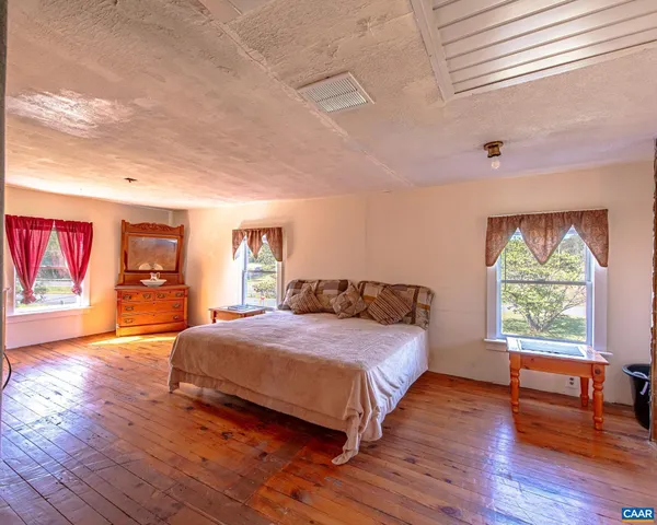 a spacious bedroom with a bed and wooden floor