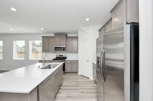 a large kitchen with stainless steel appliances granite countertop a refrigerator and a sink