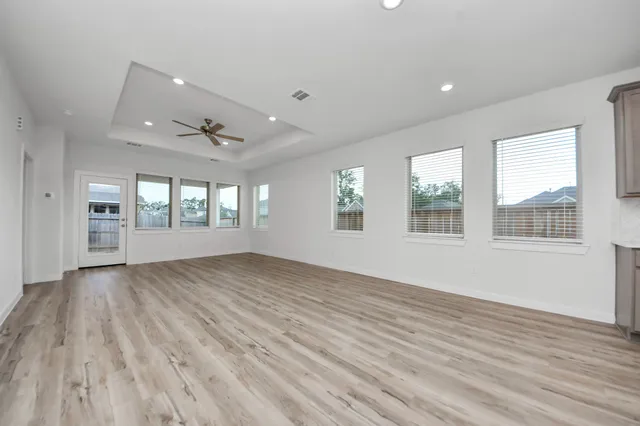 an empty room with wooden floor and windows