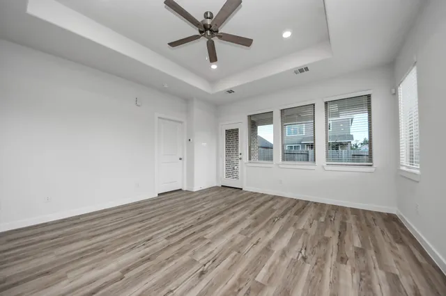 a view of empty room with wooden floor and fan