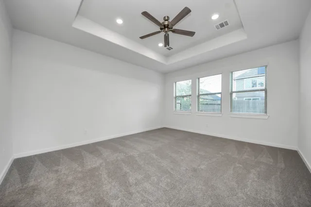 an empty room with windows and ceiling fan