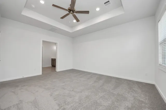 an empty room with ceiling fan and window