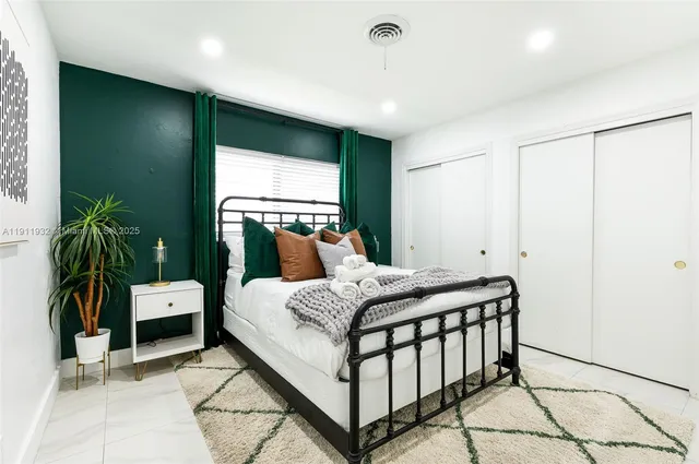 a bedroom with a bed table flowerpot and a window