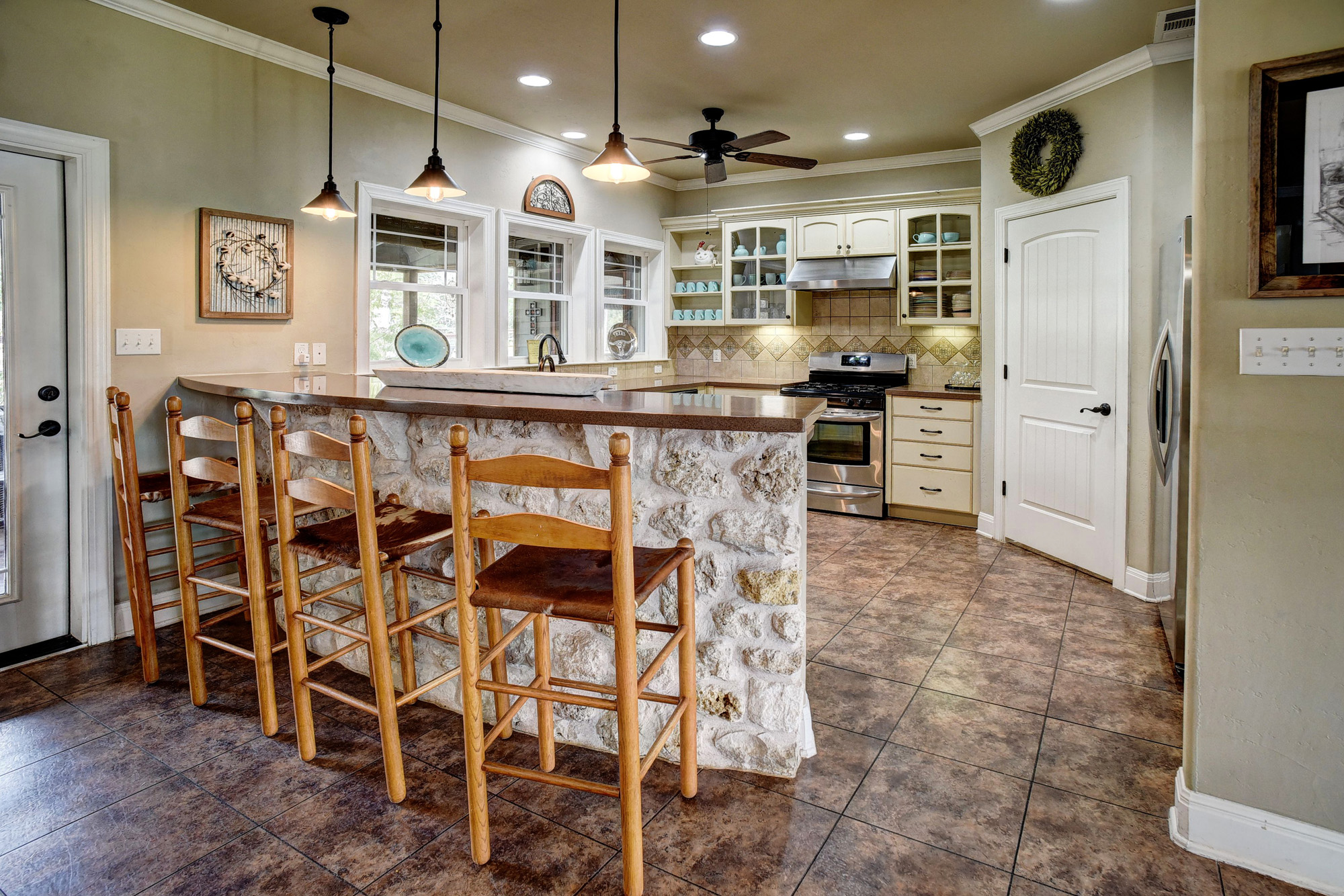 418 Vyvjala Road Smithville, TX 78957 - Photo 11 of 40 Kitchen with a breakfast bar area, appliances with stainless steel finishes, pendant lighting, a peninsula, and glass insert cabinets