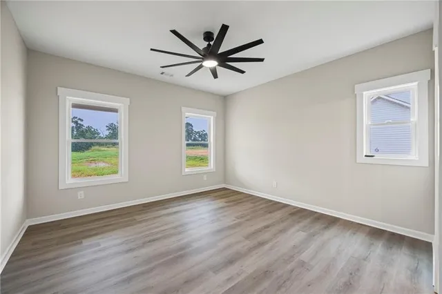 a view of a big room with wooden floor a ceiling fan and windows